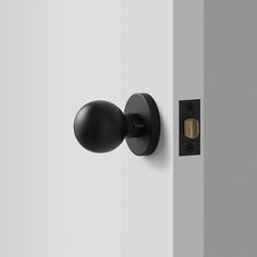 an open door with a black handle and knob on the side of it, in front of a white wall