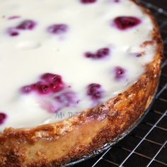 a cake with white frosting and cranberries sitting on top of a cooling rack