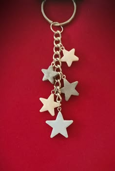 four silver and white stars hanging from a metal keychain on a red background