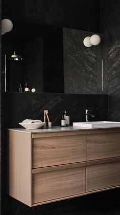 a bathroom with black walls and marble counter tops, two sinks on the opposite side