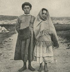 an old black and white photo of two people standing next to each other on the beach