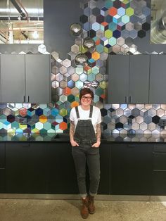 a woman standing in front of some colorful tiles