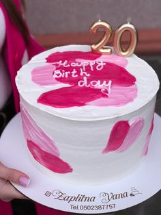 a woman holding a birthday cake with the number 20 on it and pink icing