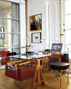 a glass table with two chairs and a laptop on it in front of a window