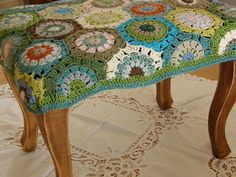 a crocheted foot stool sitting on top of a white tablecloth covered floor