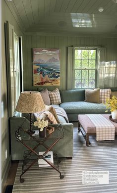 a living room filled with furniture and a large painting on the wall above it's windows