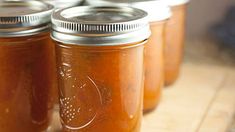 four jars filled with different kinds of food on a table top next to each other