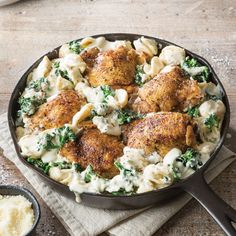 a skillet filled with chicken, pasta and spinach