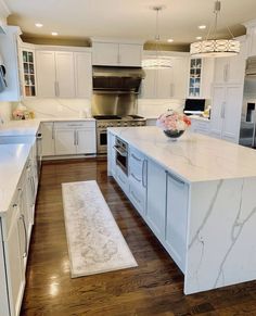 a large kitchen with white cabinets and marble counter tops