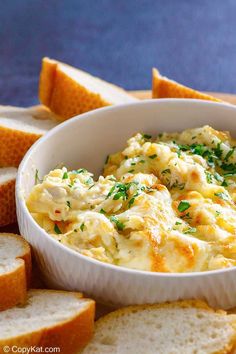 a white bowl filled with food next to slices of bread