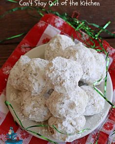 a white plate topped with snowball cookies on top of a red and white checkered table cloth