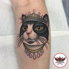 a black and white cat with a crown on it's head is shown in this tattoo