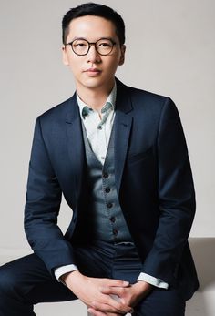 a man in a suit and glasses sitting down