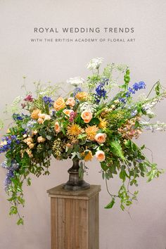 an arrangement of flowers in a vase on a wooden stand with the words royal wedding trend