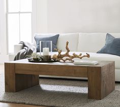 a living room with a white couch, coffee table and blue pillows on the floor