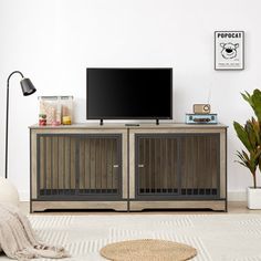 a flat screen tv sitting on top of a wooden entertainment center next to a potted plant