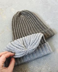 a person is holding up a knitted beanie with a knot at the top