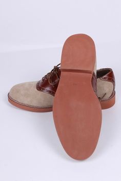 Casual men's two-tone 1950s-style oxford/saddle shoes with brogue pattern. These two-tone, 1950s-inspired, casual everyday oxfords feature an almond-shaped toe cap. The shoe is made of suede and features cognac brown full-grain leather with a brogue pattern on the backstay and around the vamp. The outsole is crafted from brown lightweight rubber with white stitching on the welt. These shoes have a casual, sporty, and authentic 50s look, pairing exceptionally well with jeans or wide trousers. The Vintage Cap Toe Oxfords With Leather Sole, Vintage Leather Slip-on Shoes With Brogue Detailing, Vintage Brown Oxfords With Stitched Sole, Vintage Leather Slip-on Shoes With Stitched Sole, Saddle Shoe, Vintage Brown Goodyear Welted Oxfords, 50s Look, 1930s Shoes, 1950s Shoes