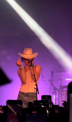 a man wearing a cowboy hat standing in front of a microphone on stage at a concert