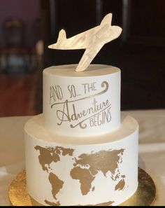 a white and gold wedding cake with an airplane on top that says and so the adventure begins