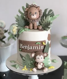 a birthday cake with a lion and monkey on it's top tier is decorated with greenery