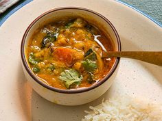 a white plate topped with a bowl of soup and rice