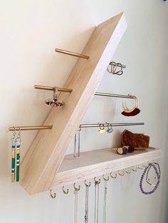 a wooden shelf with jewelry hanging from it's sides and an upside down shelf