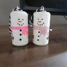 two toilet paper roll snowmen sitting on top of a wooden table next to a tv