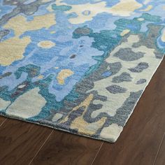 a blue and yellow rug on the floor with wood floors in front of it,