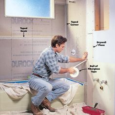 a man is working on the wall in his bathroom