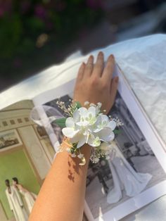 a woman's arm with flowers on it and an open magazine in the background