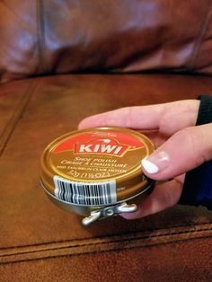 a person is holding a can of kwia on the couch with their hand