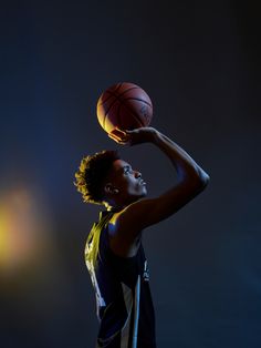 a young man holding a basketball in his right hand and looking up at the sky