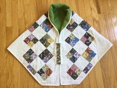 a white jacket with colorful patchwork on the front and back, sitting on top of a wooden floor