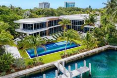 an aerial view of a house with a swimming pool in the foreground and palm trees surrounding it