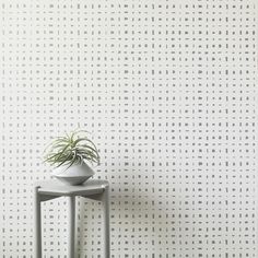 a plant is sitting on top of a small table in front of a wallpapered background