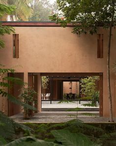 an open courtyard with trees and chairs in the foreground, surrounded by greenery