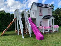 a pink slide is in front of a white house with flowers on the windowsill