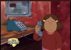 a woman holding a phone up to her ear while standing in front of a desk