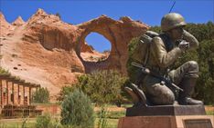 a statue of a soldier sitting in front of a rock formation with a hole in the background