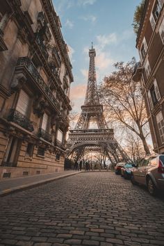 the eiffel tower in paris, france with cars parked on the side walk