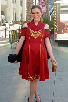 a woman in a red dress is walking down the street with her hand on her hip