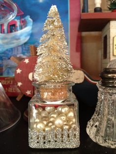 there is a small christmas tree in a glass jar on the table next to other decorations