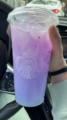 a person holding up a purple drink in their hand