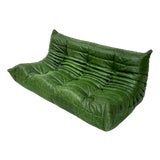 a green leather couch sitting on top of a white floor