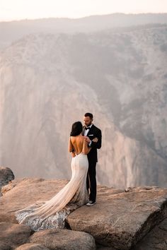 a bride and groom standing on top of a mountain