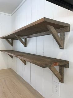 two wooden shelves on the wall in a room with white walls and wood flooring