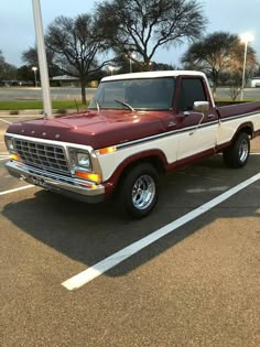 a red and white pickup truck parked in a parking lot next to a street light