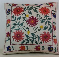 a white pillow with red and yellow flowers on the front, sitting on a shelf