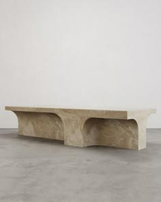 a large stone table sitting on top of a cement floor next to a white wall